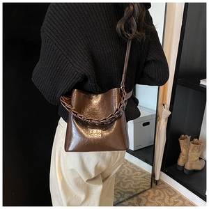 Détail du sac seau vintage en cuir ciré avec lettres dorées et sangle en chaîne
