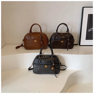 Close-up of three vintage leather boston bags in brown, grey, and black with metal clasps
