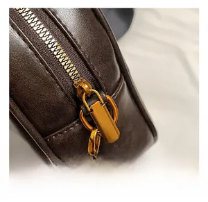 Detailed close-up of premium gold-toned zipper and hardware on a brown leather bag