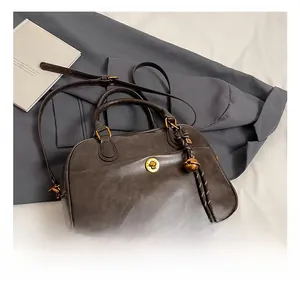 Detail of vintage coffee leather handbag with gold twist lock and bell charm on a suit