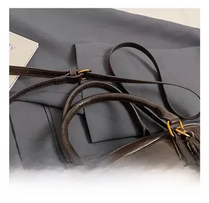 Detail of dark brown leather tote with dual handles, gold hardware, and adjustable strap