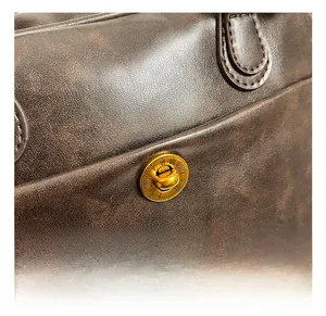 Detailed close-up of a vintage golden round buckle with Roman numerals on a brown tote bag