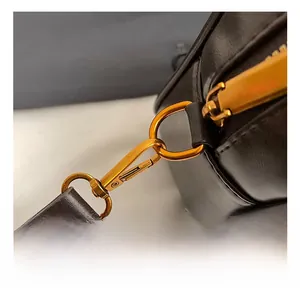 Detail of high-quality gold metal hook and textured leather strap on a brown tote bag