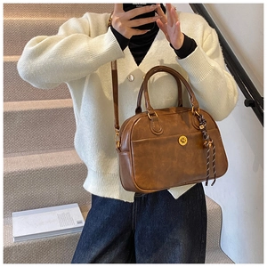 Detailed view of a brown vintage Boston bag with gold twist lock and a striped tassel