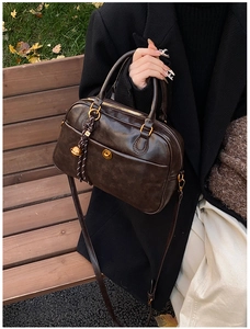 Detail of vintage brown leather pillow bag with gold clasp and letter pendant