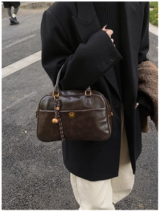 Close-up of retro dark brown boston bag with shiny leather texture and golden accents