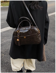 Detail of dark brown retro pillow bag with gold hardware and decorative bell charm