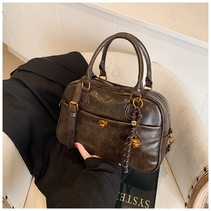 Detail of vintage textured tote with gold hardware and bell charm on a chair