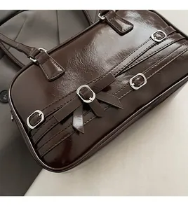 Détail d'un sac à main en cuir marron foncé avec boucles rétro et décoration de nœud