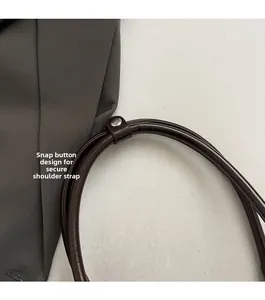 Gros plan sur la bandoulière réglable en cuir marron foncé avec bouton-pression en métal