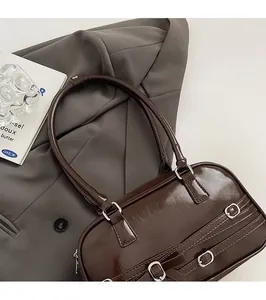 Gros plan détaillé d'un sac à bandoulière marron foncé brillant avec boucle métallique