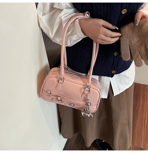 Détail du sac à main rose brillant avec lanières en nœud et pendentif papillon