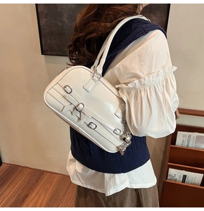 Détail du sac à bandoulière blanc crème avec nœud en cuir, boucles et pendentif cœur