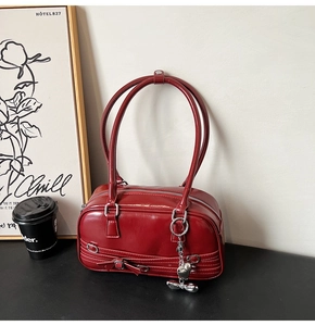 Détails d'un sac à main bordeaux brillant avec breloques argentées coeur et noeud