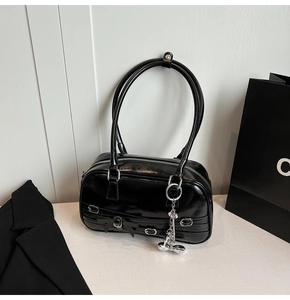 Détail d'un sac à bandoulière noir brillant avec fermeture éclair et pendentif