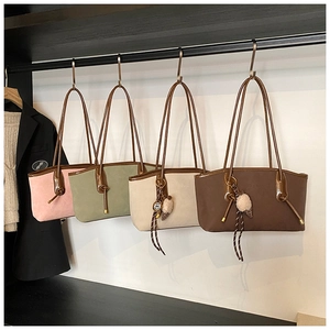 Macro detail of luxury faux suede tote bags with decorative charms on boutique display