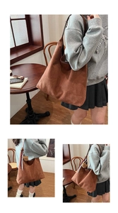 Detailed macro view of brown suede tote bag featuring a plush bear charm and long straps