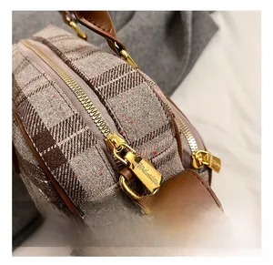 Détail de la fermeture éclair dorée et du tissu à carreaux rétro d'un sac cabas