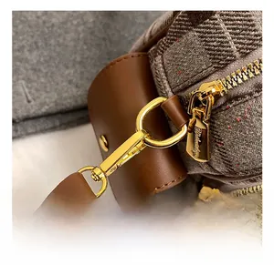 Détail macro du sac en tweed à carreaux avec fermeture éclair dorée et bordure en cuir