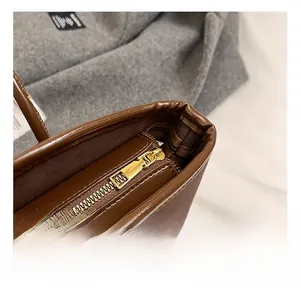 Detail view of smooth brown leather texture and premium golden zipper hardware on the tote bag