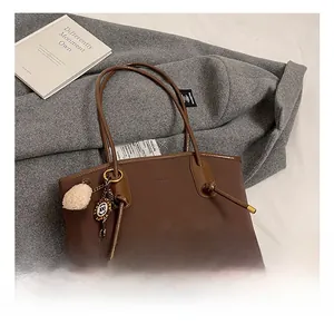 Detail of coffee brown tote bag with ice cream plush charm and vintage ring pendant