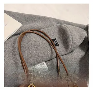 Close-up of slim double handles on a vintage dark brown leather tote bag detail