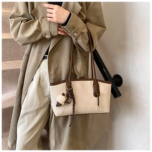 Detail of beige tote bag with brown straps, plush ice cream charm and plaid ribbon accent