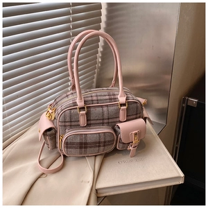 Détail d'un cabas vintage à carreaux avec poignées en cuir rose sur fond de tissu neutre