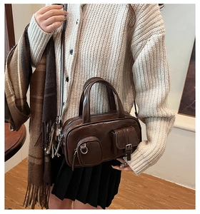 Detail of dark brown glossy leather crossbody bag styled with a warm autumn outfit