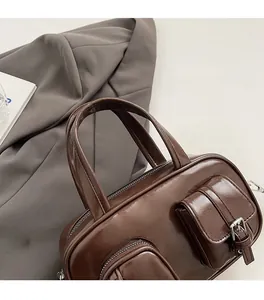Close-up of shiny dark brown leather bowling bag with dual handles and metal buckles