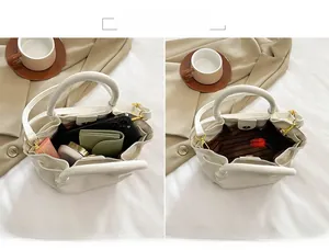 Detail of off-white pleated handbag showing spacious interior for phone and cosmetics