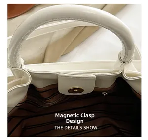 Close-up of magnetic snap closure and striped fabric lining on this white leather bag