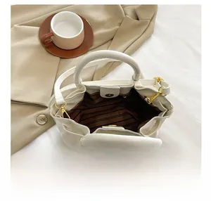 Detail shot of the striped lining and magnetic closure of the cream bucket bag on a coat