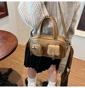 Detail of vintage caramel Boston bag with dual utility pockets shown in a cafe setting