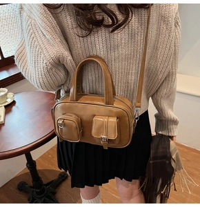 Detail of vintage brown shoulder bag with pocket accents and smooth PU leather texture