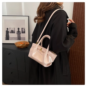 Fashionable pale pink glossy patent leather handbag with gold hardware and shoulder strap