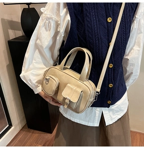Detail of cream multi-pocket Boston bag with shiny leather texture and dual handles