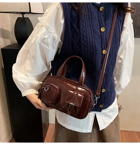 Deep red patent leather bowling bag with multi-pocket design shown in a lifestyle setting