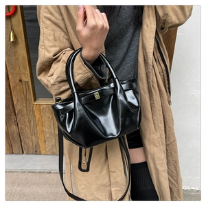 Detailed view of a black ruched handbag with gold buckle styled with a khaki coat