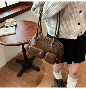 Dettaglio della borsa a spalla in pelle verniciata marrone con tasche a zip