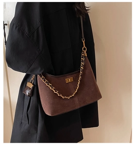 Makroaufnahme der dunkelbraunen Wildleder-Beuteltasche mit Goldkette und Minibeutel