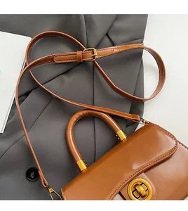 Detailed close-up of retro brown leather bag featuring a gold round twist lock and smooth texture