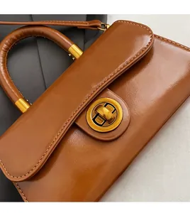 Detailed close-up of premium brown leather bag with a luxury gold circular metal lock