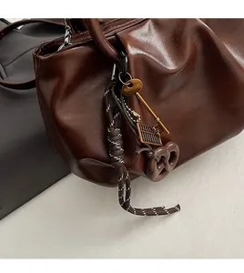 Détail d'un sac à main en cuir marron foncé avec texture plissée et bijoux vintage