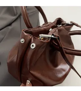 Détails de sac en cuir marron montrant la ferrure argentée et la texture de qualité