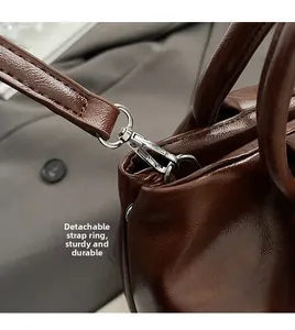 Détail des crochets en métal argenté et bandoulière amovible sur sac en cuir marron foncé