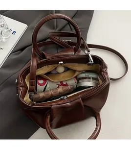 Intérieur spacieux du sac seau plissé marron montrant la poche zippée et le rangement