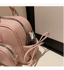 Close-up of pink leather backpack side pocket with bow detail and storage space