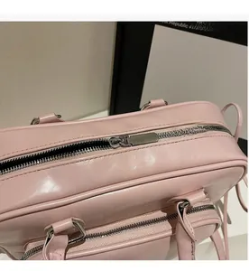 Close-up of a pink leather handbag showing the smooth silver metal zipper and stitching