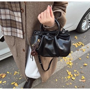Détail du sac nuage plissé noir avec breloque clé dorée et poignée circulaire